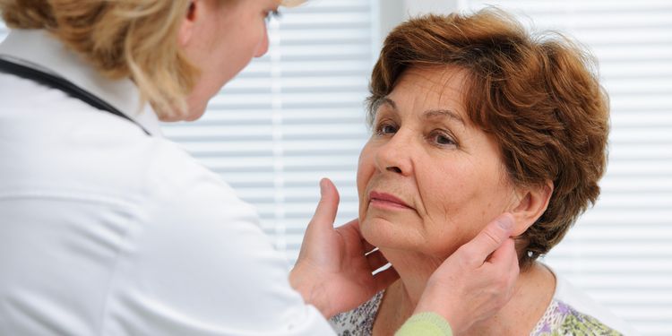 Photo of a woman at doctors office examining the thyroid gland